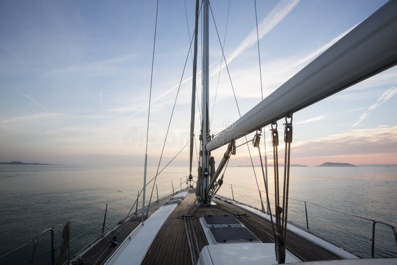 Navigation de luxe de bateau à voile en mer pendant le coucher du soleil images stock Navigation de luxe de bateau à voile en mer pendant le coucher du soleil images stock