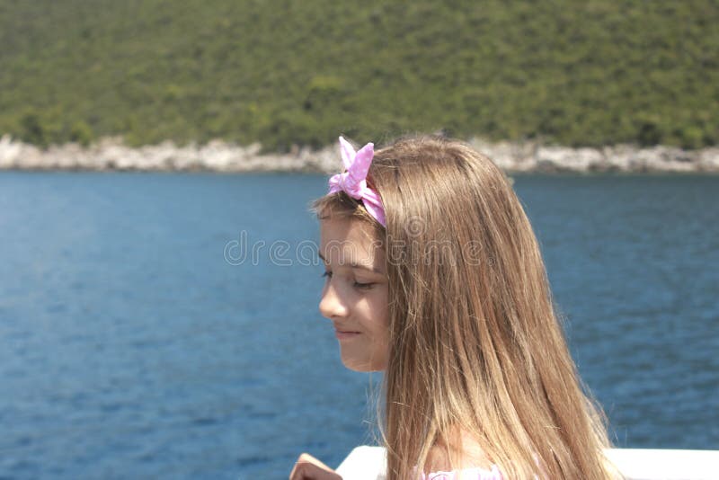 Navigação feliz da menina em um barco que sorri no mar no cruzeiro do verão imagens de stock Navigação feliz da menina em um barco que sorri no mar no cruzeiro do verão imagens de stock