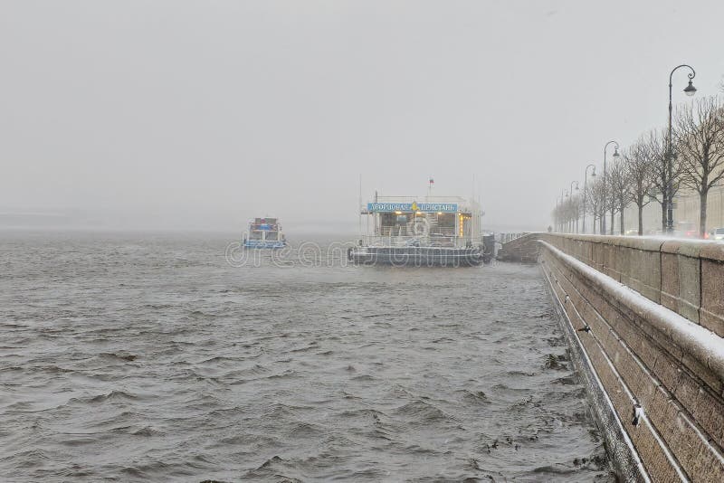 Saint Petersburg, Russia - April 19, 2024: The Palace pier. A tourist boat sails from the pier. Navigation in snowy spring bad weather. Saint Petersburg, Russia - April 19, 2024: The Palace pier. A tourist boat sails from the pier. Navigation in snowy spring bad weather