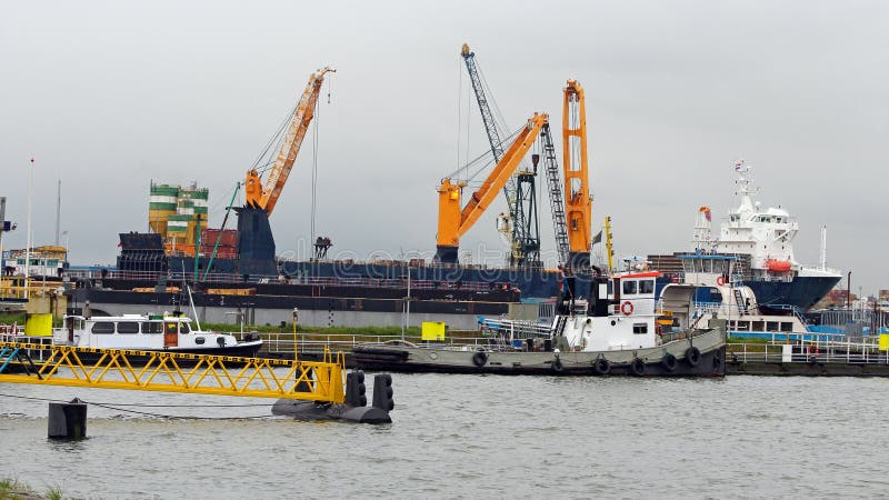 Navio de carga do portador de maioria com os guindastes da plataforma sob a carga no porto foto de stock Navio de carga do portador de maioria com os guindastes da plataforma sob a carga no porto foto de stock