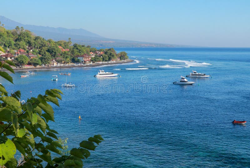 Navios de cruzeiros e barcos de pesca tradicionais ancorados na segurança da baía de Bali em Indonésia As ondas bateram a barreir imagens de stock Navios de cruzeiros e barcos de pesca tradicionais ancorados na segurança da baía de Bali em Indonésia As ondas bateram a barreir imagens de stock