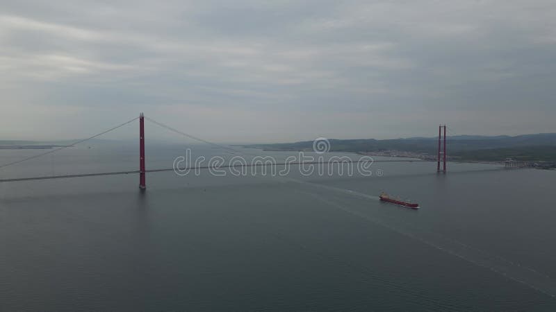 Navire à cargaison rouge naviguant sous un grand pont suspendu en Turquie clips vidéos