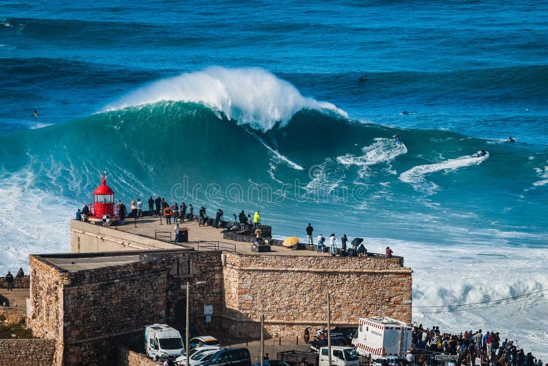 Nazare portugal surfer ridande gigantisk våg framför nazare fyr