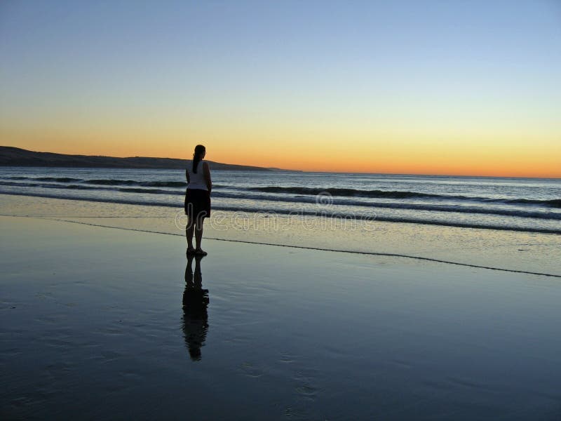 Picture of young woman looking forlornly out to see silhouetted by sunset. Picture of young woman looking forlornly out to see silhouetted by sunset