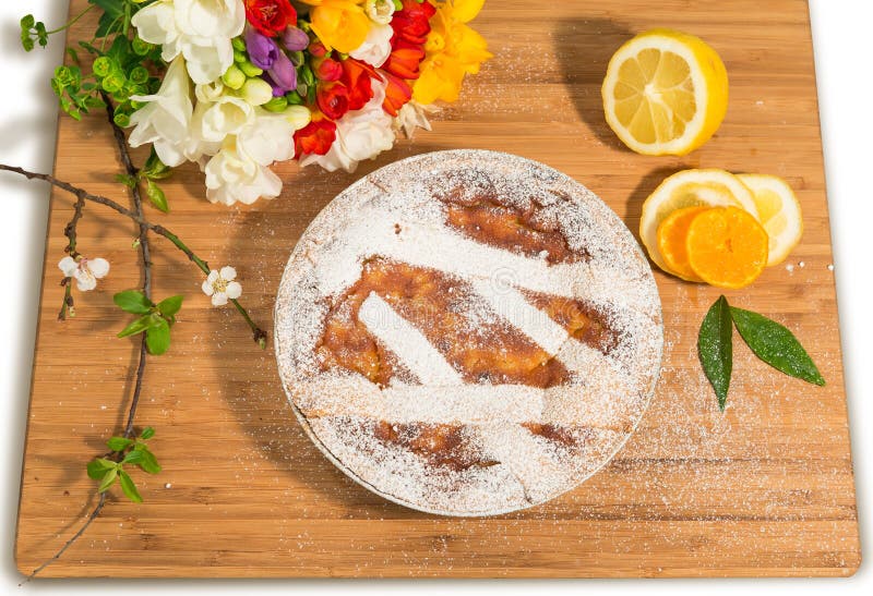 Neapolitan easter pie sprinkled with icing sugar and decorated with freesia and fresh fruits.