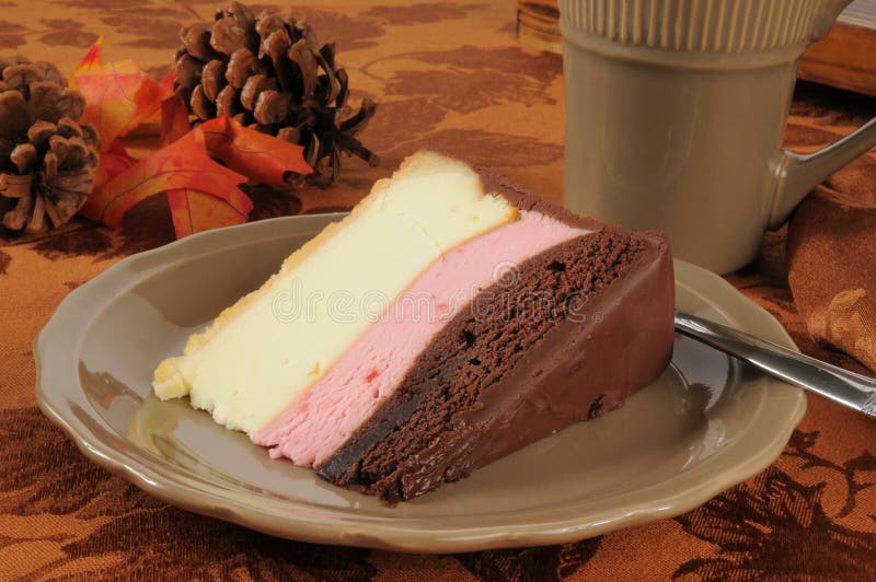 A slice of gourmet neapolitan cheesecake with a hot drink. A slice of gourmet neapolitan cheesecake with a hot drink