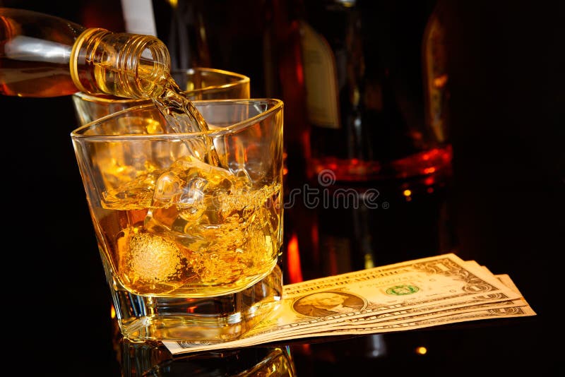 Near hällande whisky för bartendern framme av whiskyexponeringsglas och flaskor dollar fotografering för bildbyråer Near hällande whisky för bartendern framme av whiskyexponeringsglas och flaskor dollar fotografering för bildbyråer