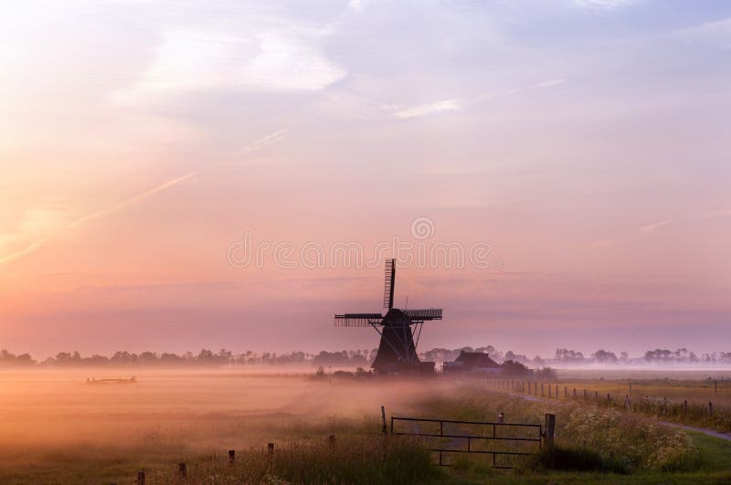 Nederlandse windmolen in mist in de vroege ochtend stock fotografie Nederlandse windmolen in mist in de vroege ochtend stock fotografie