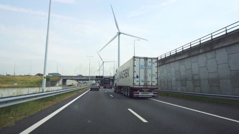 Nederländerna Rotterdam, circa Juli, 2018: Rida på en industriområde av Rotterdam, med vindgeneratorer