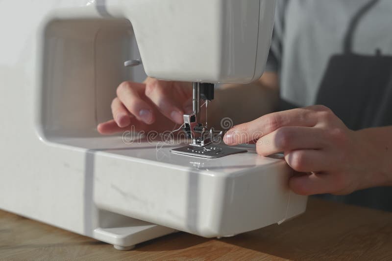 Needlewoman Hands Inserting Thread through Needle Hole in Sewing