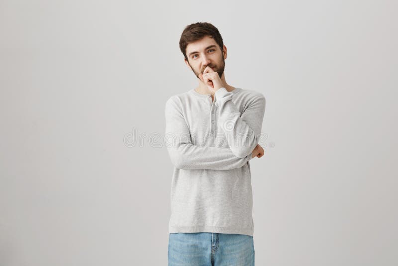 He needs to make decision. Indoor portrait of thoughtful handsome bearded male model holding hand on chin and lips royalty free stock photos He needs to make decision. Indoor portrait of thoughtful handsome bearded male model holding hand on chin and lips royalty free stock photos