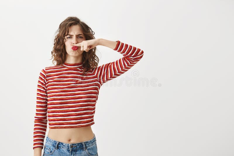 Neem te ernstige het geen leven Gevoels speelse vrouw in gestreepte bebouwde hoogste holdingswijsvinger onder neus alsof hebbend stock foto Neem te ernstige het geen leven Gevoels speelse vrouw in gestreepte bebouwde hoogste holdingswijsvinger onder neus alsof hebbend stock foto