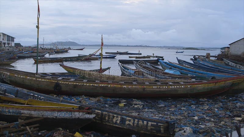 Neglected canoes at a polluted shoreline, Conakry