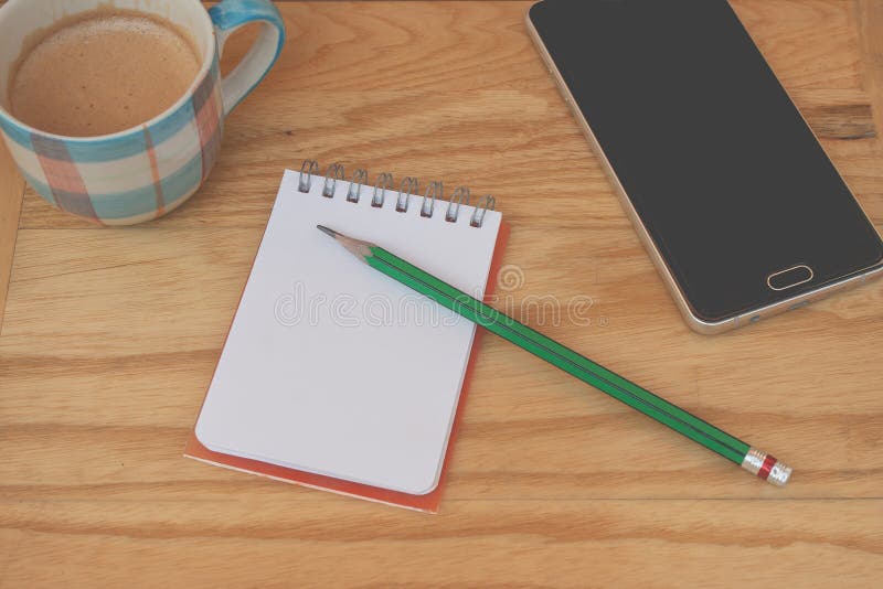 Negocio creativo y concepto de la idea: el lápiz verde usado puesto en el cuaderno con la taza del smartphone y de café puso la t imagenes de archivo Negocio creativo y concepto de la idea: el lápiz verde usado puesto en el cuaderno con la taza del smartphone y de café puso la t imagenes de archivo