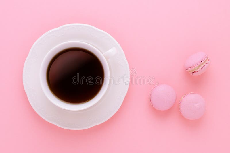 Negro de la taza de café con los macarrones hechos a mano en fondo rosado desde arriba foto de archivo Negro de la taza de café con los macarrones hechos a mano en fondo rosado desde arriba foto de archivo