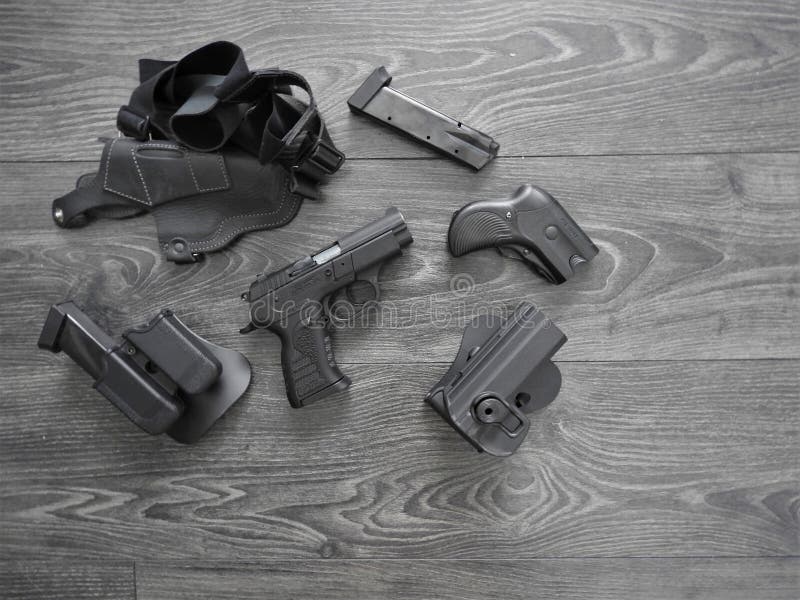 Negro del arma, revistas de repuesto y pistolera de cuero en fondo gris imagen de archivo Negro del arma, revistas de repuesto y pistolera de cuero en fondo gris imagen de archivo
