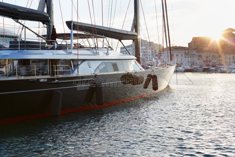 Negro moderno un barco de vela rojo en el puerto de Cannes en la puesta del sol imagenes de archivo Negro moderno un barco de vela rojo en el puerto de Cannes en la puesta del sol imagenes de archivo