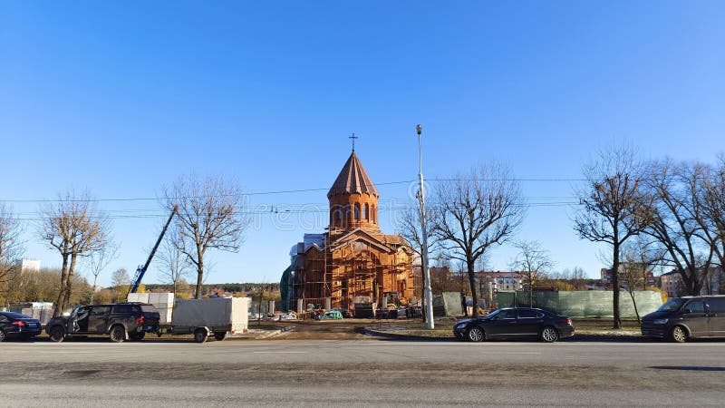 Nei pressi di una strada cittadina, con una torre e una croce, è stata costruita una chiesa di mattoni rossi, con alberi parcheggi. Nei pressi di una strada cittadina è stata costruita una chiesa di mattoni rossi, con una torre e una croce, con alberi parcheggiati e una linea elettrica con pali metallici e luci. tempo solare autunnale
