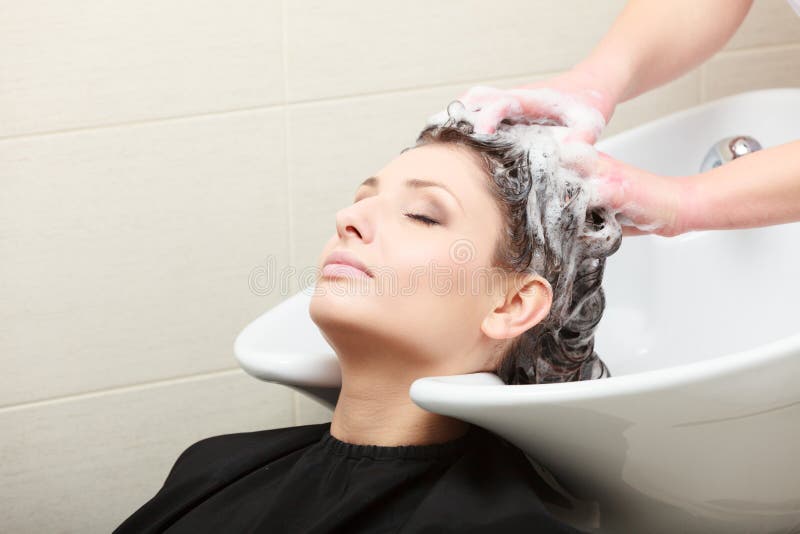 Nel salone di lavoro di parrucchiere. Cliente della donna dei capelli di lavaggio del parrucchiere. immagini stock libere da diritti Nel salone di lavoro di parrucchiere. Cliente della donna dei capelli di lavaggio del parrucchiere. immagini stock libere da diritti