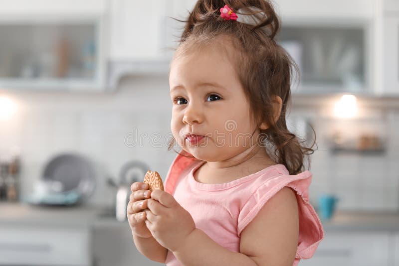 Neonata adorabile che mangia biscotto saporito immagini stock libere da diritti Neonata adorabile che mangia biscotto saporito immagini stock libere da diritti