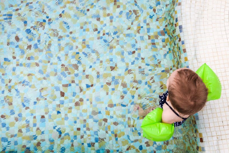 Neonata con i bracciali gonfiabili Bambino che impara nuotare in stagno fotografia stock libera da diritti Neonata con i bracciali gonfiabili Bambino che impara nuotare in stagno fotografia stock libera da diritti
