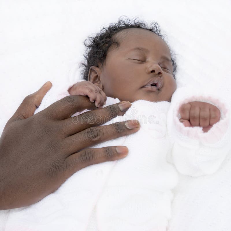 Neonata di un mese che dorme mentre tenendo la sua mano dei father’s fotografia stock Neonata di un mese che dorme mentre tenendo la sua mano dei father’s fotografia stock