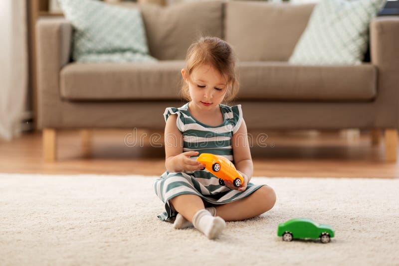 Neonata felice che gioca con l'automobile del giocattolo a casa immagini stock Neonata felice che gioca con l'automobile del giocattolo a casa immagini stock
