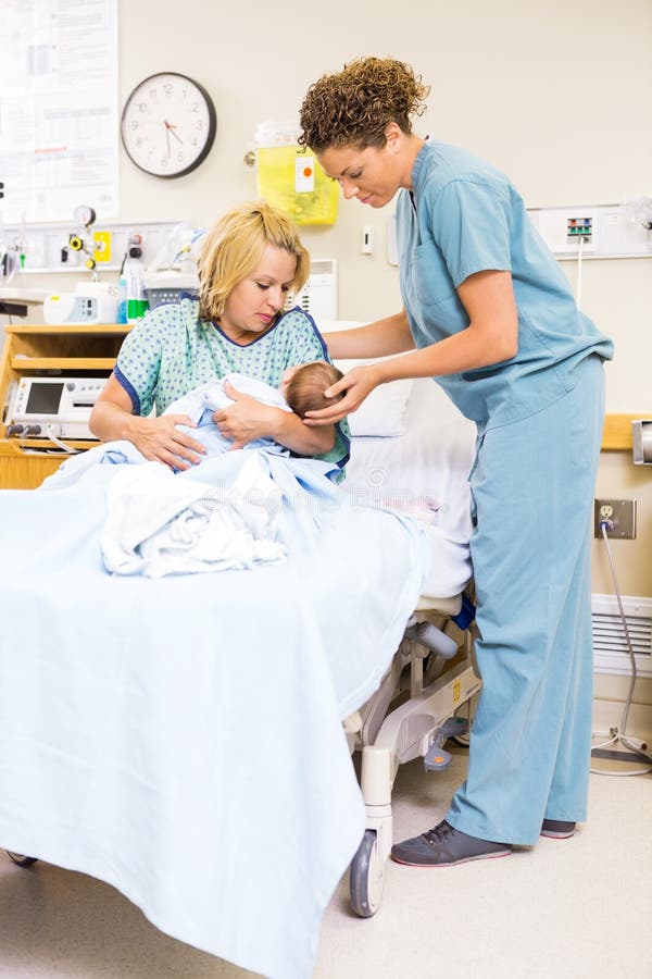Neonato della tenuta di Assisting Woman In dell'infermiere a fotografie stock libere da diritti Neonato della tenuta di Assisting Woman In dell'infermiere a fotografie stock libere da diritti