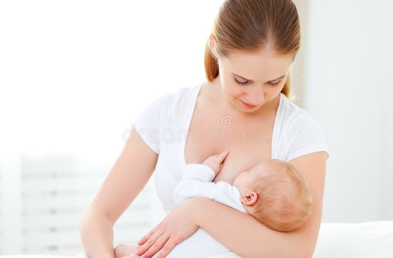 Neonato di allattamento al seno della madre in letto bianco