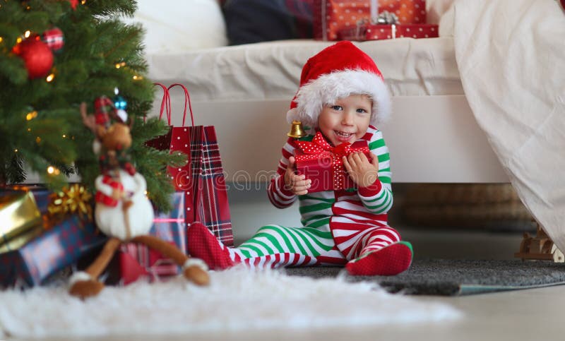Neonato di Appy in pigiami con i regali sulla mattina di natale vicino fotografia stock libera da diritti Neonato di Appy in pigiami con i regali sulla mattina di natale vicino fotografia stock libera da diritti