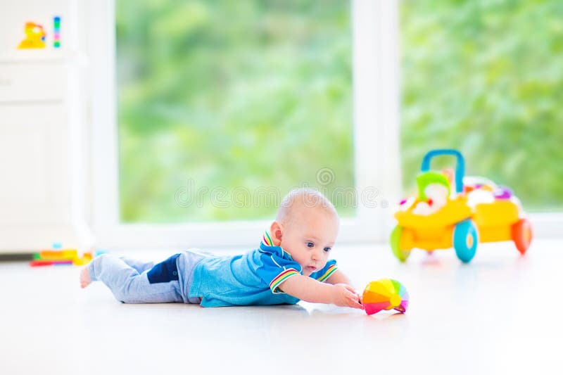 Adorable baby boy playing with a colorful ball and toy car in a white room. Adorable baby boy playing with a colorful ball and toy car in a white room