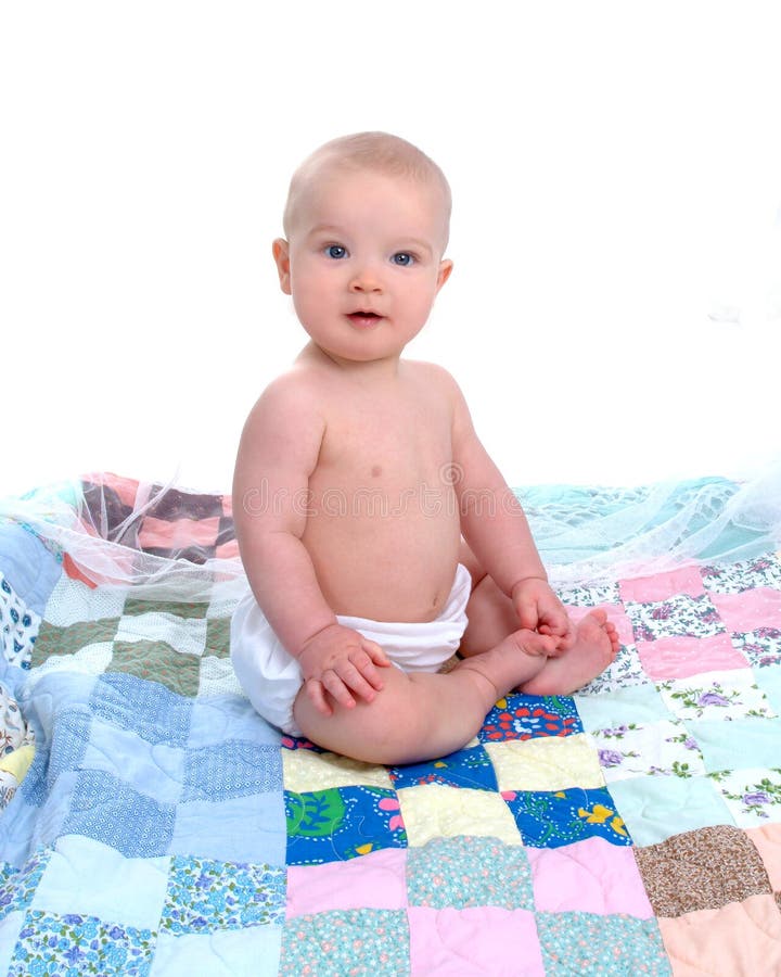 Baby boy sitting in front of white background on a multicolored quilt. Baby boy sitting in front of white background on a multicolored quilt