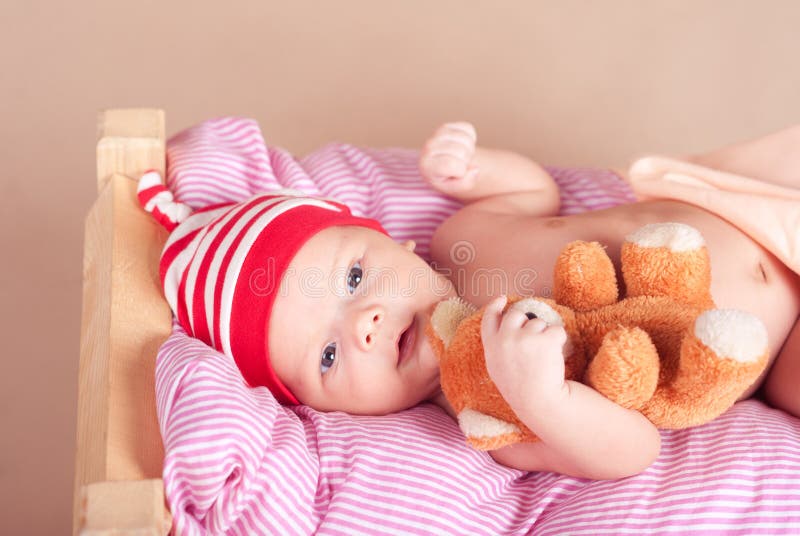 Neonato sveglio che dorme con l'orsacchiotto a letto fotografie stock Neonato sveglio che dorme con l'orsacchiotto a letto fotografie stock