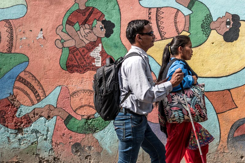 Nepalese people walking by colourful graffiti