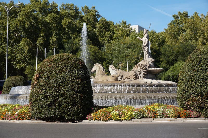 Neptune Statue in Downtown Madrid Spain. Photo of statue of neptune and water fountain in downtown madrid spain with trees and flowers Neptune Statue in Downtown Madrid Spain. Photo of statue of neptune and water fountain in downtown madrid spain with trees and flowers