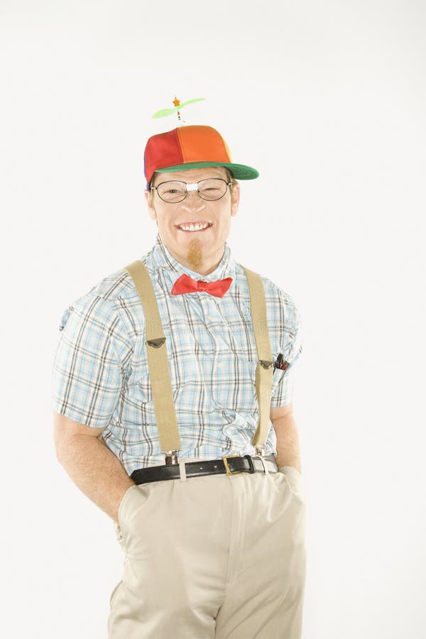 Nerd smiling. Caucasian young man dressed like nerd wearing propeller cap with hands in pockets looking at viewer with big smile stock image Nerd smiling. Caucasian young man dressed like nerd wearing propeller cap with hands in pockets looking at viewer with big smile stock image