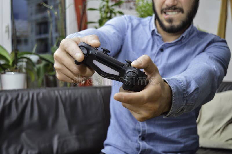 Nervöse junge Holding-Spielauflage des gut aussehenden Mannes und Spielen zu den Videospielen lizenzfreies stockbild Nervöse junge Holding-Spielauflage des gut aussehenden Mannes und Spielen zu den Videospielen lizenzfreies stockbild