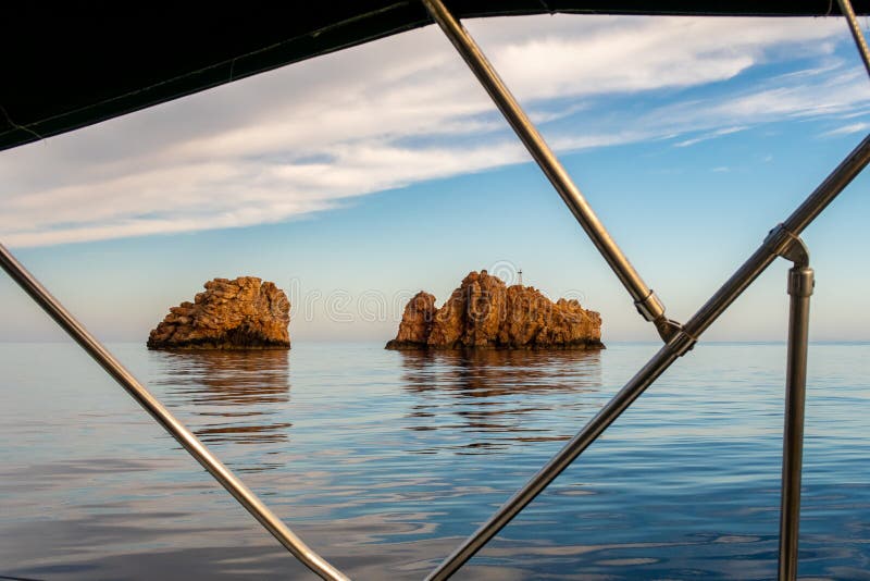 Nes Portes Rocks with a cross on top, north of Paros Island sticking out from perfectly flat Mediterranean Sea, Greece