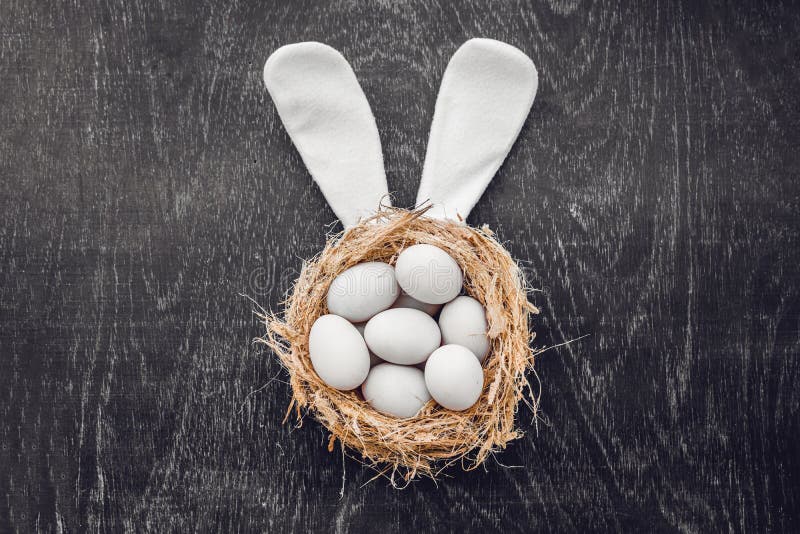 A nest with three white Easter eggs and bunny ears at home on Easter day. Celebrating Easter at spring. Painting eggs royalty free stock images A nest with three white Easter eggs and bunny ears at home on Easter day. Celebrating Easter at spring. Painting eggs royalty free stock images