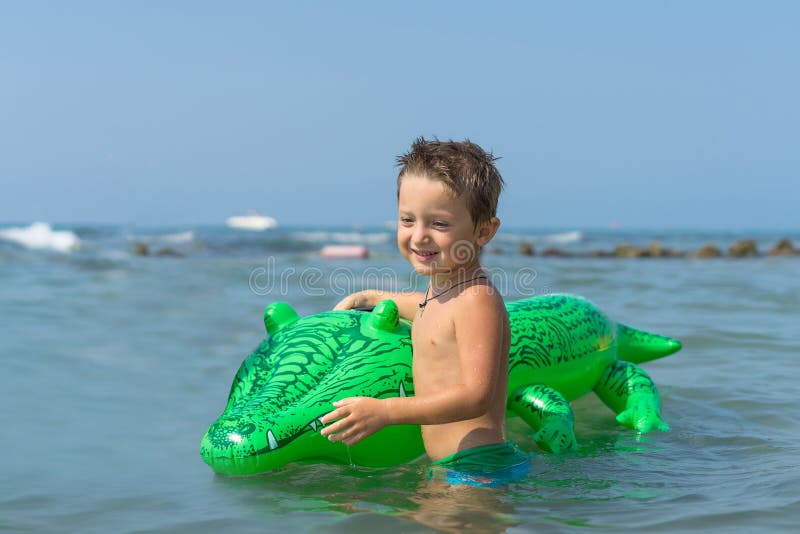 Neto que joga e que espirra na água do mar Retrato do menino feliz da criança na praia de fotografia de stock royalty free Neto que joga e que espirra na água do mar Retrato do menino feliz da criança na praia de fotografia de stock royalty free