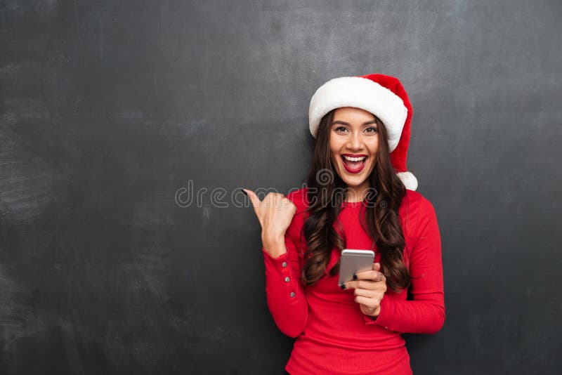 Nette Brunettefrau im roten Blusen- und Weihnachtshut lizenzfreie stockfotos