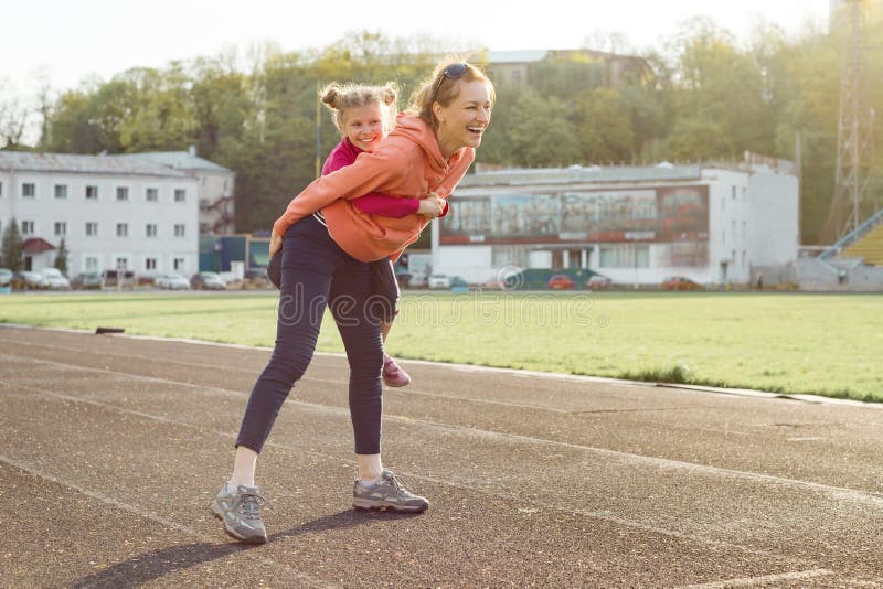 Nette Familie des Sports, gesunder Lebensstil, Frühlingsporträt der Mutter und wenig Tochter, die Spaß und Betrieb am Stadion hat stockbild Nette Familie des Sports, gesunder Lebensstil, Frühlingsporträt der Mutter und wenig Tochter, die Spaß und Betrieb am Stadion hat stockbild