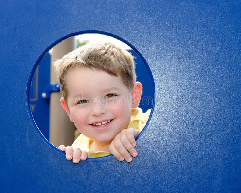 Cute child peeks through hole at playground outdoors at park. Cute child peeks through hole at playground outdoors at park.