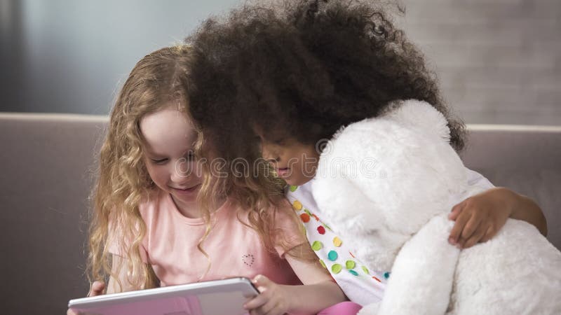 Nette Kleinkinder, die auf Sofa, aufpassendes lustiges Video am Telefon, Geräte sitzen lizenzfreie stockfotos Nette Kleinkinder, die auf Sofa, aufpassendes lustiges Video am Telefon, Geräte sitzen lizenzfreie stockfotos