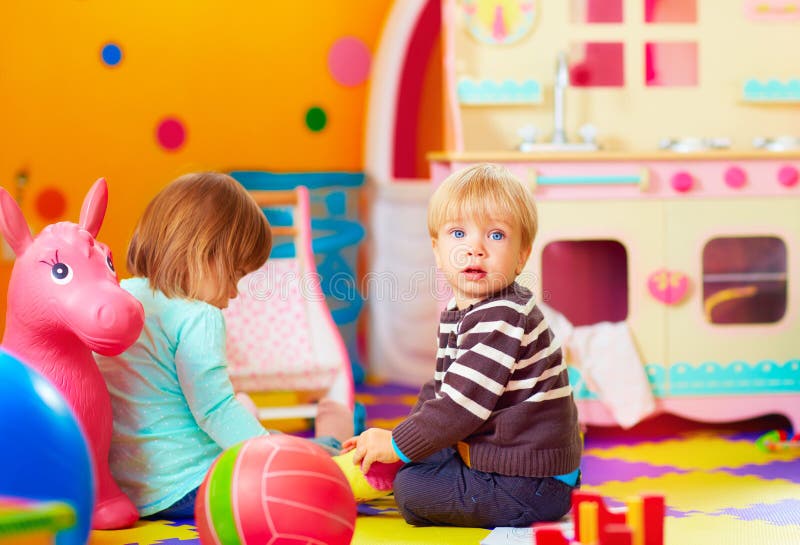 Nette Kleinkinder, die zusammen in Kindertagesstätte spielen lizenzfreie stockfotografie Nette Kleinkinder, die zusammen in Kindertagesstätte spielen lizenzfreie stockfotografie