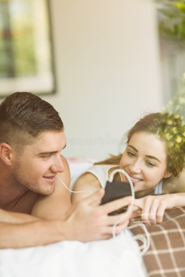 Nette Paare, die auf dem Bett hört Musik liegen stockbild Nette Paare, die auf dem Bett hört Musik liegen stockbild