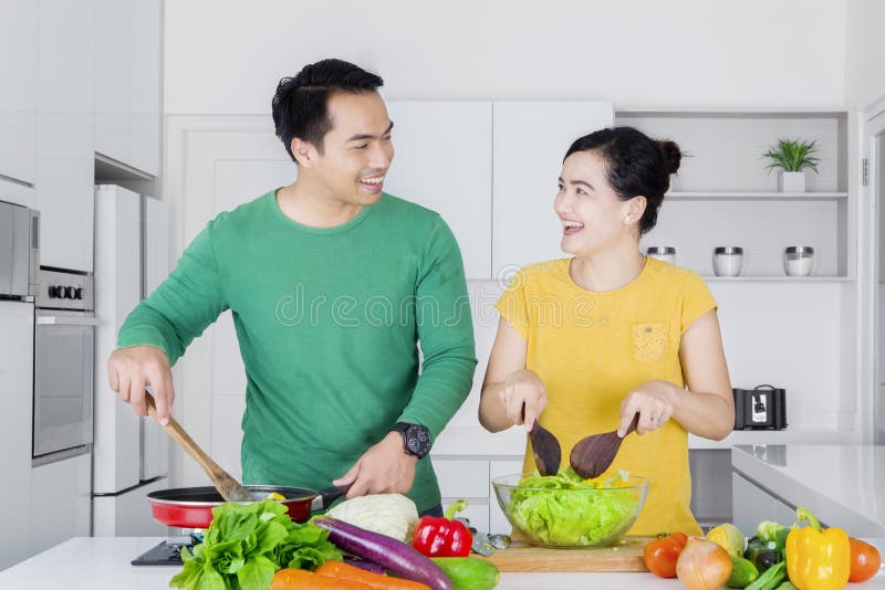 Nette Paare, die zu Hause kochen lizenzfreies stockbild Nette Paare, die zu Hause kochen lizenzfreies stockbild