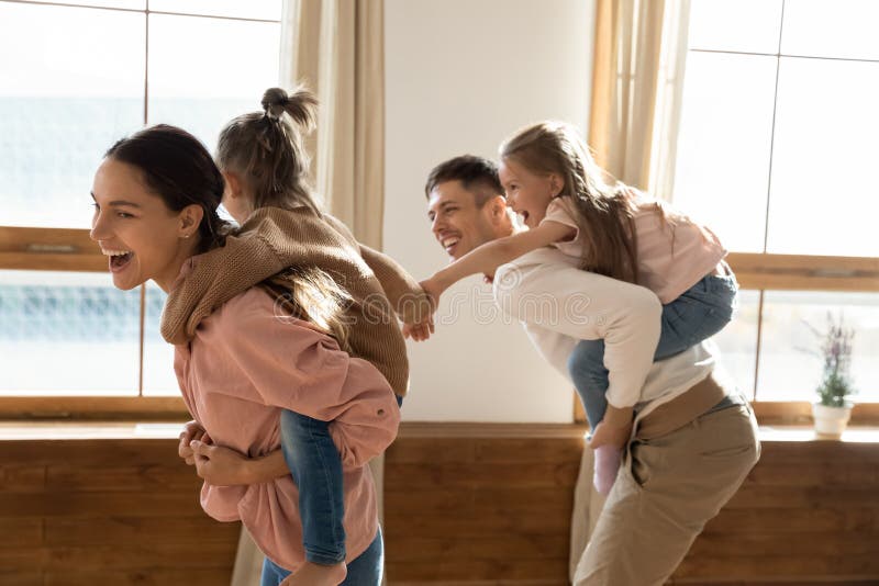 Nette Paare tragen reitene kleinen Töchter angehängt, gemeinsam zu Hause zu spielen lizenzfreie stockfotos