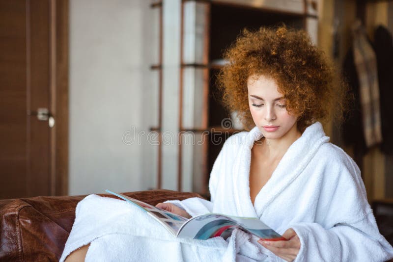 Nette reizende ruhige Frau, die zu Hause sitzt und Zeitschrift liest lizenzfreie stockbilder Nette reizende ruhige Frau, die zu Hause sitzt und Zeitschrift liest lizenzfreie stockbilder