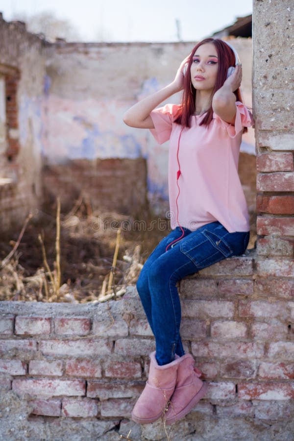 Step into a captivating moment of serenity and joy as you witness this adorable redhead woman immersing herself in the bliss of music. Against the backdrop of red brick ruins at sunset, she finds solace and happiness in her white earphones, effortlessly blending the beauty of the past with the enchantment of the present. With selective focus enhancing her charming expression, this vertical image captures the essence of pure enjoyment and appreciation for life's simple pleasures. Let the warmth of the sunset and the soothing melodies transport you to a world of tranquility and contentment. Perfect for lifestyle blogs, music enthusiasts, and those seeking inspiration in the little moments that make life truly delightful. Step into a captivating moment of serenity and joy as you witness this adorable redhead woman immersing herself in the bliss of music. Against the backdrop of red brick ruins at sunset, she finds solace and happiness in her white earphones, effortlessly blending the beauty of the past with the enchantment of the present. With selective focus enhancing her charming expression, this vertical image captures the essence of pure enjoyment and appreciation for life's simple pleasures. Let the warmth of the sunset and the soothing melodies transport you to a world of tranquility and contentment. Perfect for lifestyle blogs, music enthusiasts, and those seeking inspiration in the little moments that make life truly delightful.